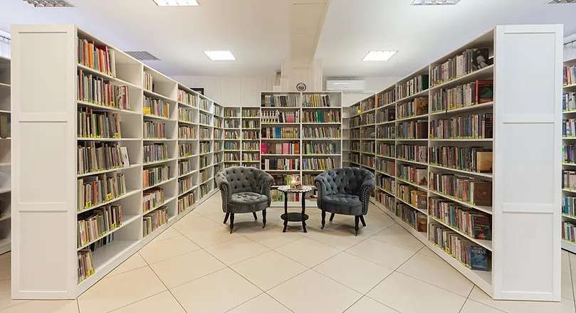 Wnętrze biblioteki, regały z książkami i miejsce do czytania